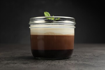 Tasty panna cotta with blackberries and mint in jar at grey table, closeup