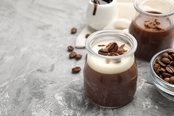 Delicious panna cotta with chocolate chunks and coffee beans on grey textured table, closeup. Space for text