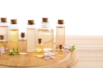 Bottles of essential oils and different plants on wooden table against white background