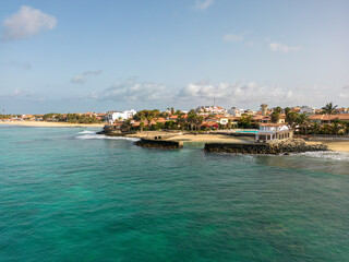Aerial drone shot of the Santa Maria pier and beach, Sal Island, Cape Verde, at golden sunset. Turquoise waters, fishing boats and a tropical atmosphere in high resolution.
