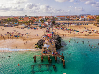 Aerial drone shot of the Santa Maria pier and beach, Sal Island, Cape Verde, at golden sunset. Turquoise waters, fishing boats and a tropical atmosphere in high resolution.