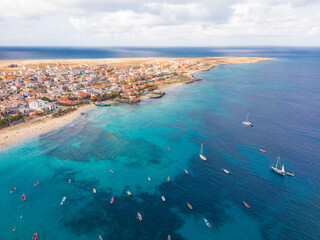 Aerial drone shot of the Santa Maria pier and beach, Sal Island, Cape Verde, at golden sunset. Turquoise waters, fishing boats and a tropical atmosphere in high resolution.