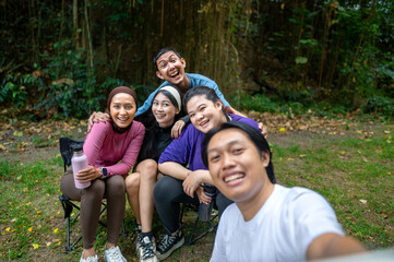 Fototapeta premium Indonesian southeast asian people in a sporty outfit taking a selfie together after practice exercise in a public park outdoors. Concept of a Healthy active lifestyle