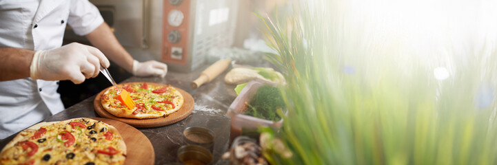 Chef Decorates Pizza in Kitchen Wide Banner with Copy Space