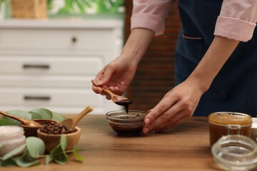 Woman making natural body scrub at wooden table, closeup