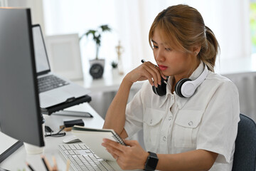 An Asian female software developer concentrating on handwritten notes in a sleek tech workspace