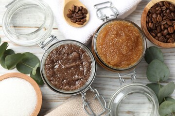 Natural body scrubs in glass jars and ingredients on wooden table, flat lay