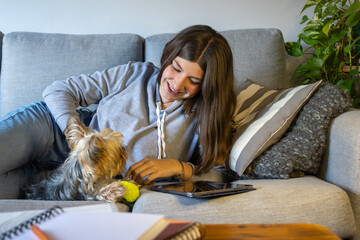Smiling teenager playing with her dog at home.Copy space.Natural light