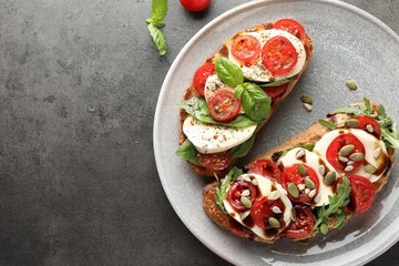 Delicious sandwiches with mozzarella cheese and tomatoes on grey table, top view. Space for text