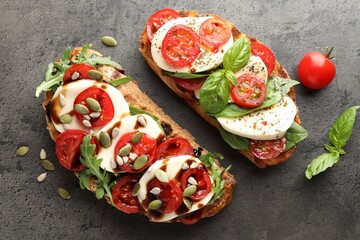 Delicious sandwiches with mozzarella cheese and tomatoes on grey table, flat lay