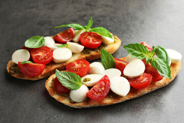 Delicious sandwiches with mozzarella cheese, tomatoes and basil on grey textured table, closeup