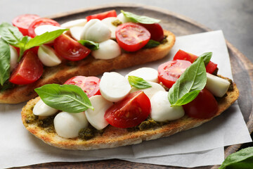 Delicious sandwiches with mozzarella cheese, tomatoes and basil on grey table, closeup