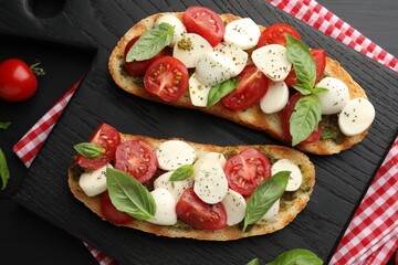 Delicious sandwiches with mozzarella cheese, tomatoes and basil on black wooden table, flat lay