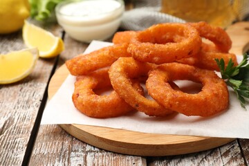 Fried squid rings served with sauce on wooden table, closeup
