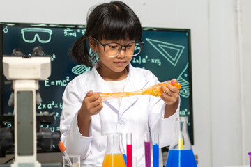 Young Scientist in Lab: A young, curious girl, adorned in a crisp lab coat and spectacles, meticulously examines a vibrant chemical experiment.