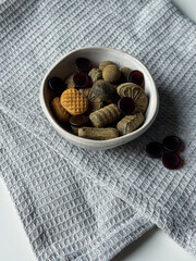 Different licorice candies in small bowl on white table and grey kitchen towel