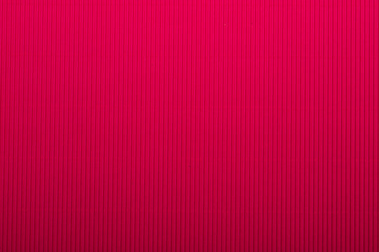 A vibrant rose corrugated surface with a ribbed texture, perfect for use as an abstract background.