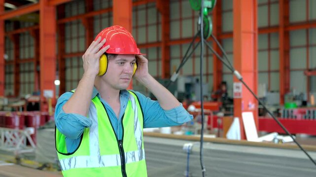 Working at industrial machinery in factory. Technician engineer wearing and adjust protective safety ear plug Safety equipment for industry factory.