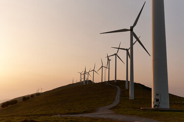 Wind turbines line the Oiz mountains, Bizkaia, Spain, during a golden sunset. A symbol of sustainable energy and a brighter tomorrow.