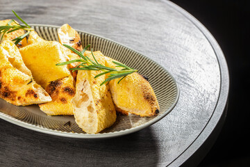 Golden slices of freshly baked focaccia bread with rosemary served on a ceramic plate