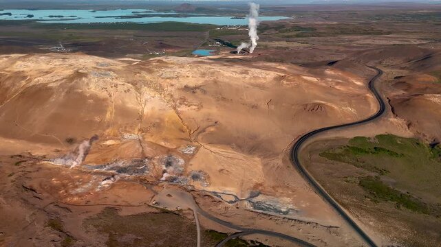 Explore the striking geothermal landscapes of Iceland featuring undulating hills, lush valleys, winding roads, and columns of steam rising from the earth. Hverir Myvatn Iceland