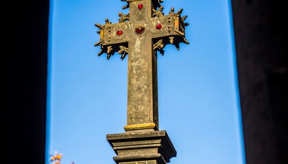 Ornate cross with intricate details against a vibrant blue sky, highlighting the rich craftsmanship and religious symbolism.