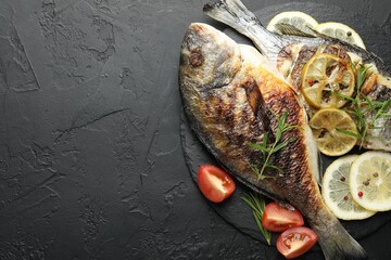 Homemade seafood dish. Tasty roasted dorado fish with spices and tomato on black table, flat lay. Space for text