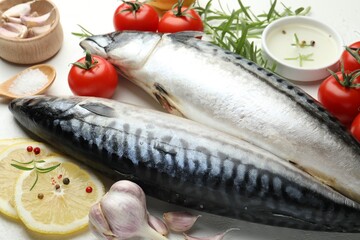 Fresh raw mackerels and spices on white table, closeup. Seafood delicacies