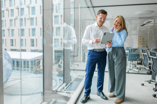 Pair of professionals collaborating in a modern office with large windows in a vibrant urban environment