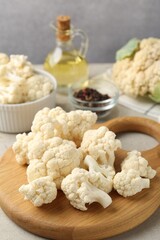 Fresh raw cauliflower florets and spices on light grey table, closeup
