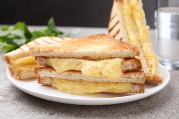 Tasty sandwiches with melted cheese and parsley on grey table, closeup