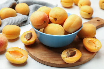 Fresh ripe apricots in bowl on white marble table, closeup