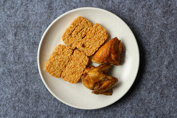 Fried tempeh and fried chicken served on a white plate