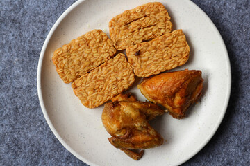 Fried tempeh and fried chicken served on a white plate