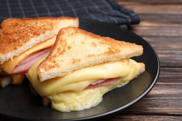 Delicious sandwiches with melted cheese and ham on wooden table, closeup