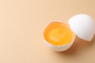 Broken chicken egg on beige background, closeup. Space for text