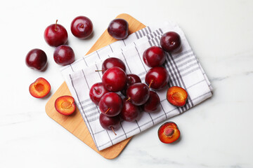 Ripe cherry plums on white marble table, flat lay