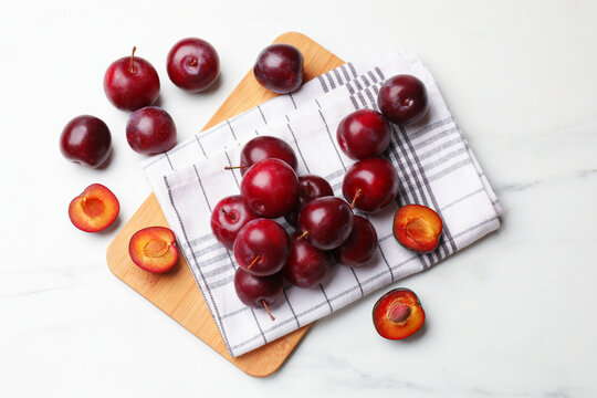 Ripe cherry plums on white marble table, flat lay