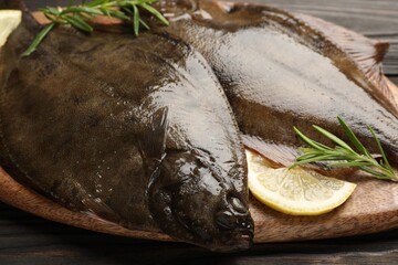 Fresh flounder fish, lemon and rosemary on wooden table, closeup. Raw seafood