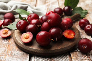 Whole and cut cherry plums on color wooden table, closeup