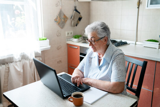 Senior woman using laptop at home for video call, eHealth meeting, education, virtual conference. Elderly person enjoying online communication, family connection. Technology lifestyle in retirement