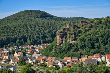 A view of the Jungfernsprung rock formation near Dahn, with a prominent stone pillar topped with a tree, overlooking the forested Pfälzerwald valley 