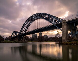 Obraz premium Steel arch bridge over a river at sunset