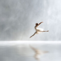 Fototapeta premium Elegant ballerina leaps gracefully above reflective water. Expresses freedom, artistry, and ethereal beauty. Ideal for dance, art, and inspirational themes.