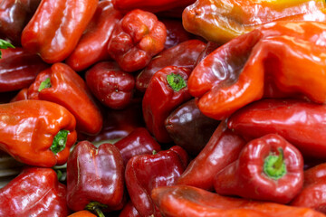 Close-up of fresh red bell peppers piled in bulk, showing vibrant color, smooth texture, and natural ripeness at the market.