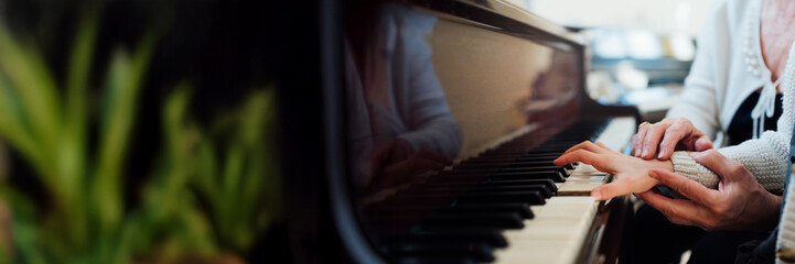 Obraz premium Hands on Piano Keys Wide Banner with Copy Space