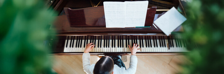 Piano Player's Hands on Keys with Sheet Music Wide Banner