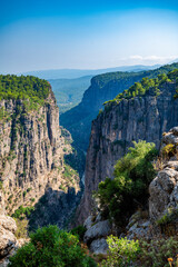 Sunlight illuminates the impressive tazi canyon, revealing steep cliffs covered in vibrant green vegetation, creating a breathtaking natural landscape in antalya, turkey