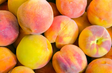 Fresh ripe peaches with vibrant yellow and pink skin close up