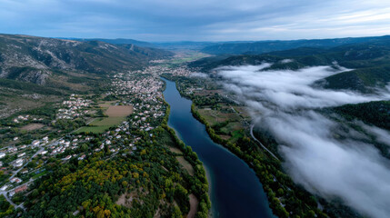 An expansive aerial view showcasing a verdant valley and winding river, accented by clouds and a lush landscape, instilling feelings of awe and appreciation for nature's beauty.
